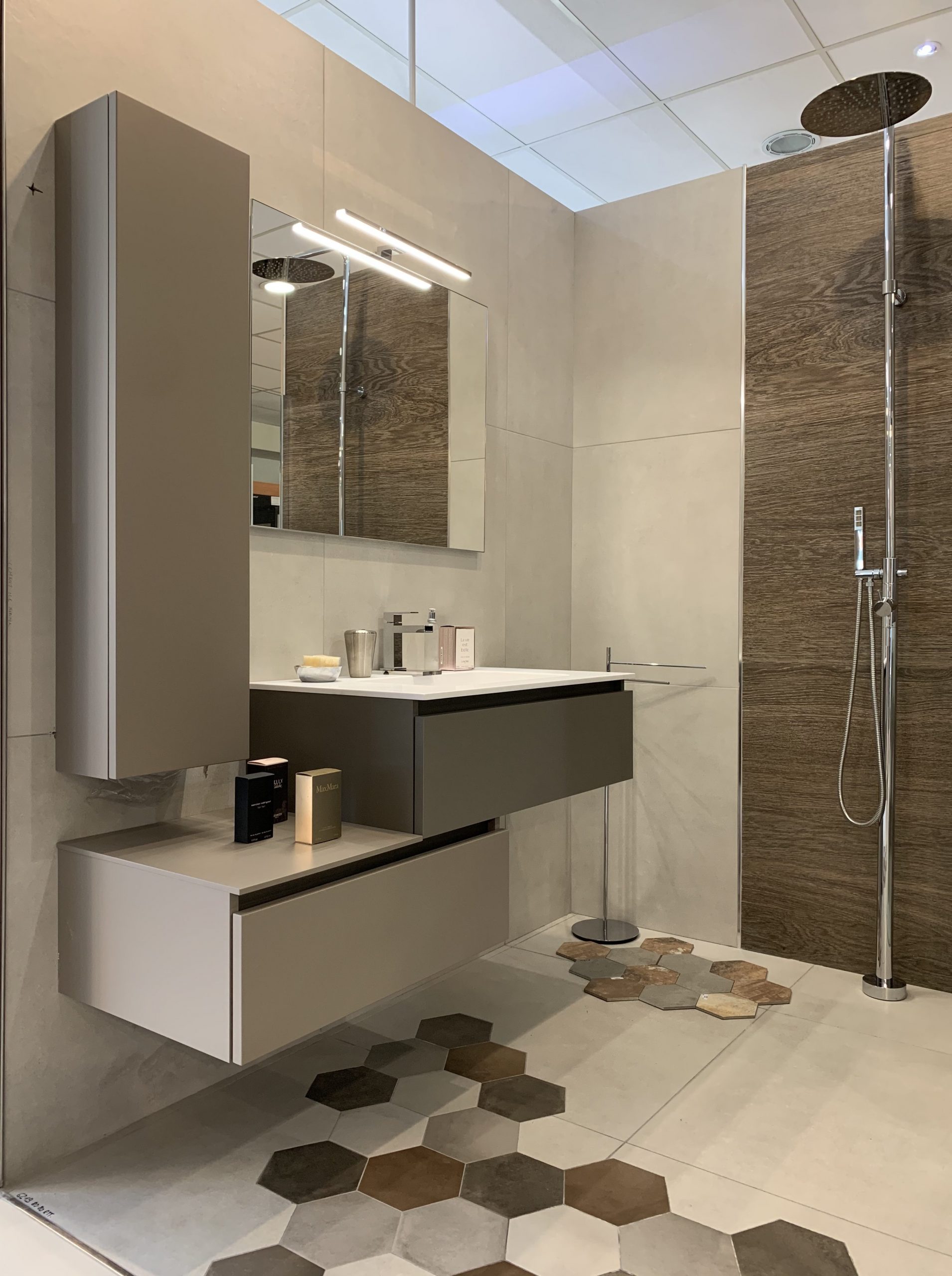 Immagine raffigurante un lavandino con dei mobili e uno specchio. Sulla destra dell'immagine si vede un soffione della doccia.